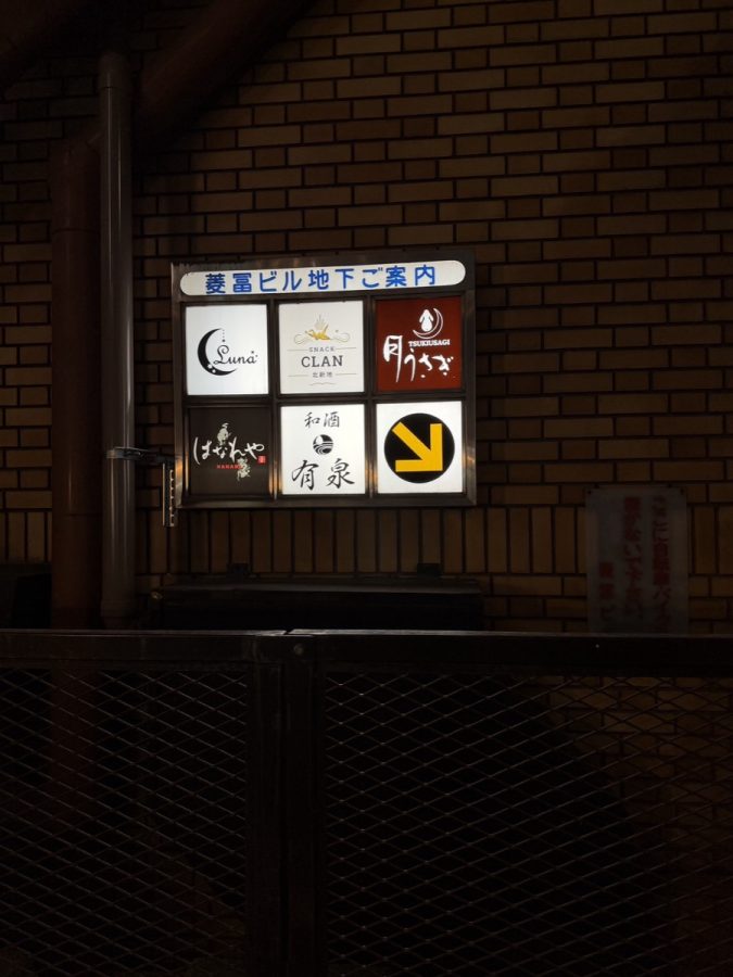 菱冨ビル地下ご案内の看板。SNACK CLANのロゴと地下への矢印