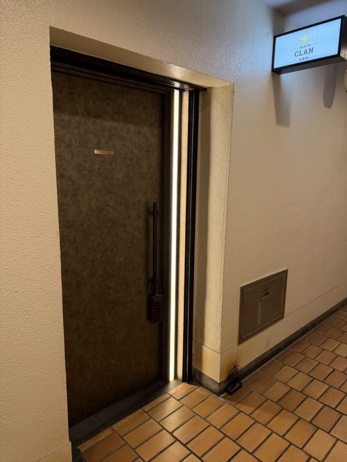 SNACK CLANの入口。ダークブラウンの扉の横にSNACK CLAN 北新地の看板